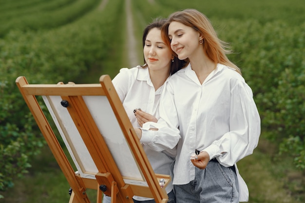 Elegante und schöne Mädchen, die in einem Feld malen