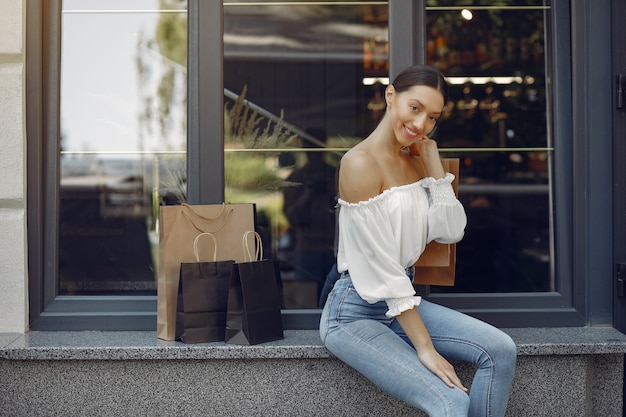 Elegante und stilvolle Mädchen auf der Straße mit Einkaufstüten