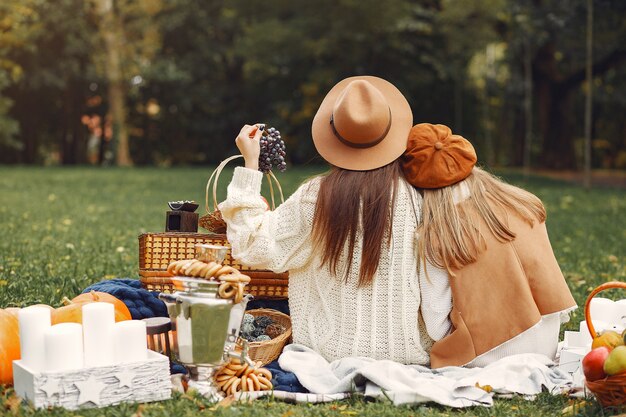 Elegante und stilvolle Mädchen, die in einem Herbstpark sitzen