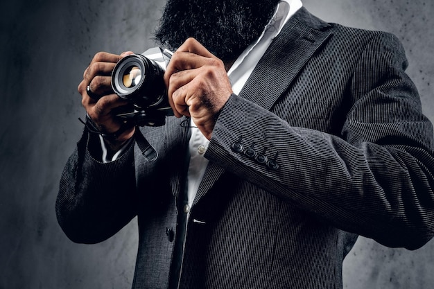 Eleganter bärtiger professioneller Fotograf im Anzug, der mit einer kompakten DSLR-Kamera fotografiert.