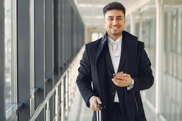 Eleganter Mann am Flughafen mit einem Koffer