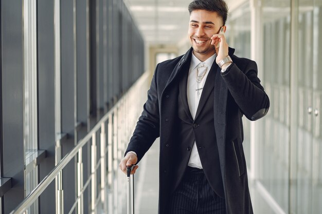 Eleganter Mann am Flughafen mit einem Koffer