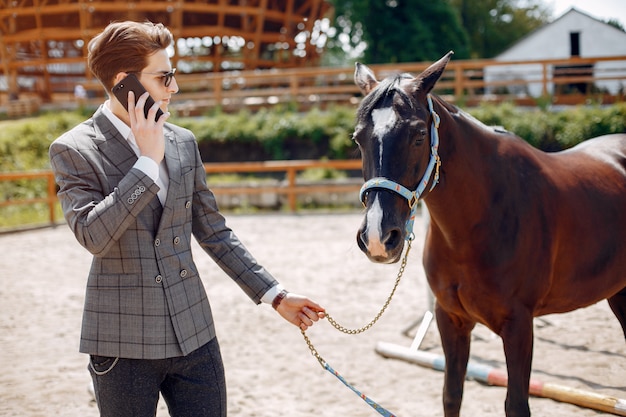 Eleganter Mann, der nahe bei Pferd in einer Ranch steht