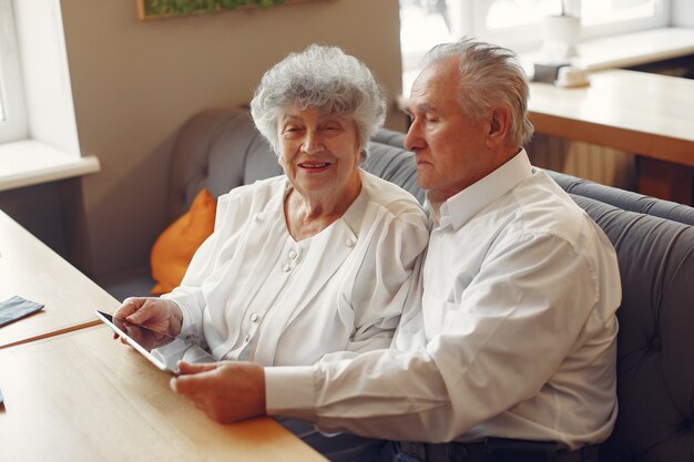 Elegantes altes Ehepaar in einem Café mit einer Tablette