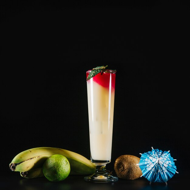 Elegantes Cocktail und exotische Früchte auf schwarzem Hintergrund