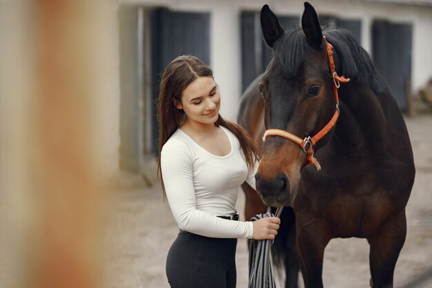 Elegantes Mädchen in einem Bauernhof mit einem Pferd