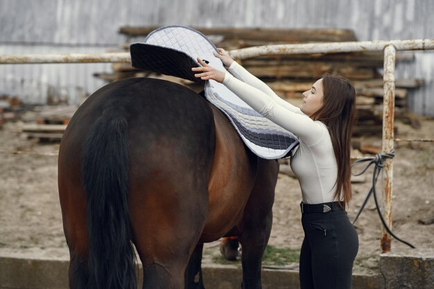 Elegantes Mädchen in einem Bauernhof mit einem Pferd