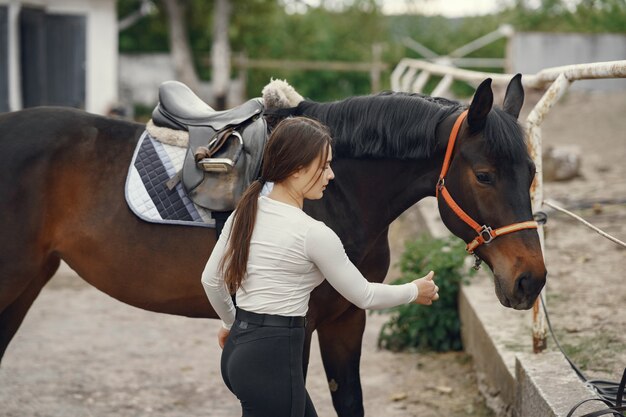 Elegantes Mädchen in einem Bauernhof mit einem Pferd