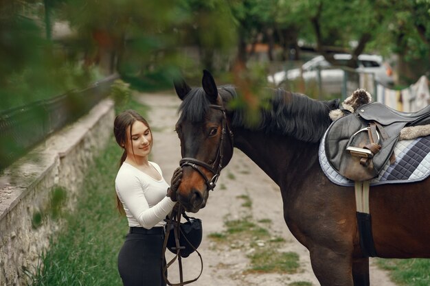 Elegantes Mädchen in einem Bauernhof mit einem Pferd