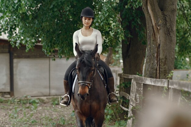 Elegantes Mädchen in einem Bauernhof mit einem Pferd