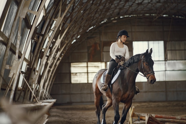 Elegantes Mädchen in einem Bauernhof mit einem Pferd