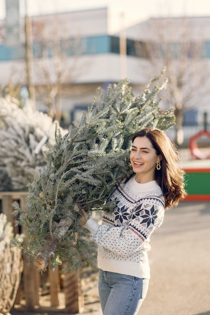 Elegantes Mädchen kauft einen Weihnachtsbaum.