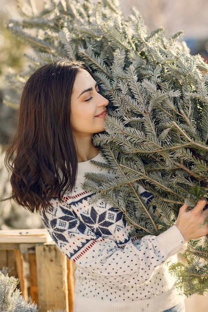 Elegantes Mädchen kauft einen Weihnachtsbaum.