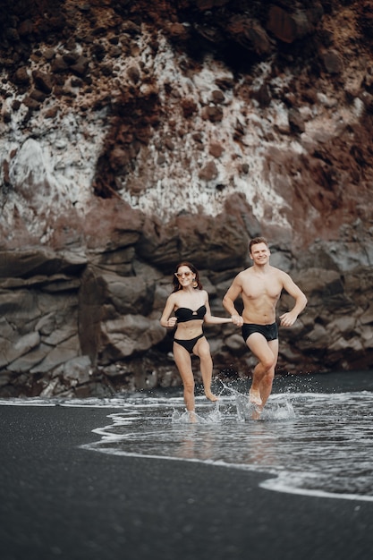 Elegantes Paar an einem Strand in der Nähe von Felsen