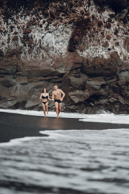 Elegantes Paar an einem Strand in der Nähe von Felsen