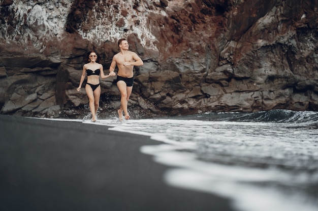 Elegantes Paar an einem Strand in der Nähe von Felsen