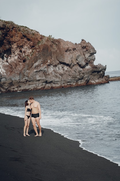 Elegantes Paar an einem Strand in der Nähe von Felsen