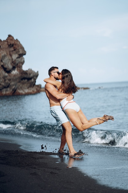 Elegantes Paar an einem Strand in der Nähe von Felsen