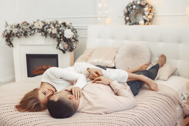 Elegantes Paar, das auf einem Bett in einer Weihnachtsdekoration sitzt