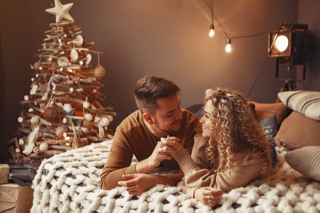 Elegantes Paar, das zu Hause nahe Weihnachtsbaum sitzt