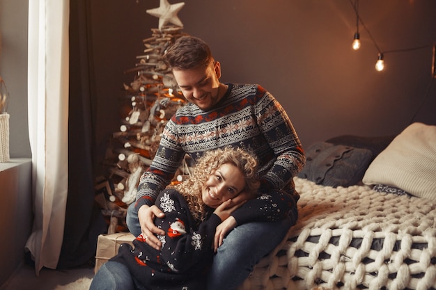 Elegantes Paar, das zu Hause nahe Weihnachtsbaum sitzt