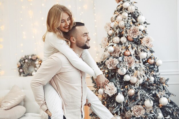 Elegantes Paar, das zu Hause nahe Weihnachtsbaum steht