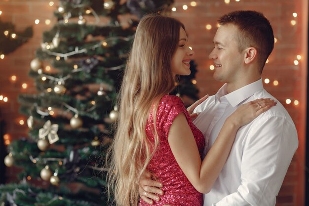 Elegantes Paar zu Hause in der Nähe von Weihnachtsbaum