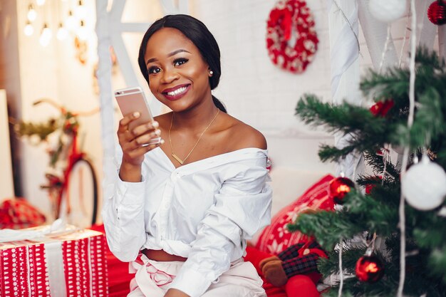 Elegantes schwarzes Mädchen in den Weihnachtsdekorationen