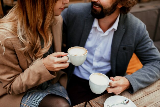 Elegantes verliebtes Paar, das in einem Café sitzt, Kaffee trinkt, sich unterhält und die Zeit miteinander genießt. Selektiver Fokus auf Tasse.