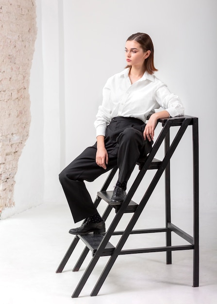 Elegantes weibliches Modell, das in der Treppe in einem Jackenanzug aufwirft. neues Weiblichkeitskonzept