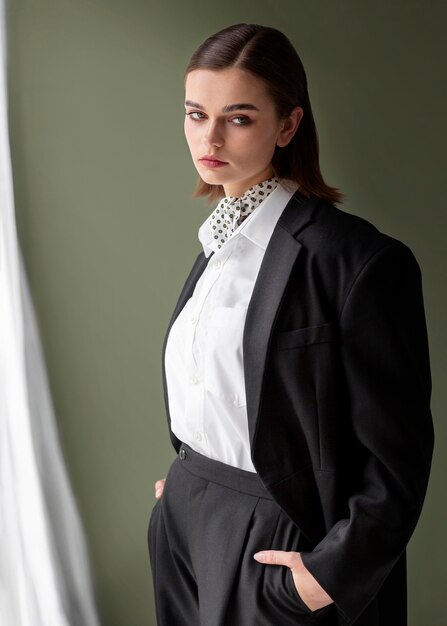 Elegantes weibliches Modell, das in einem Jackenanzug mit einer Krawatte aufwirft. neues Weiblichkeitskonzept