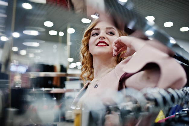 Eleganz blondes Mädchen im Mantel im Laden von Pelzmänteln und Lederjacken