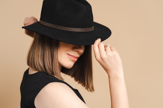 Eleganzporträt einer jungen stilvollen Frau mit schwarzem Hut