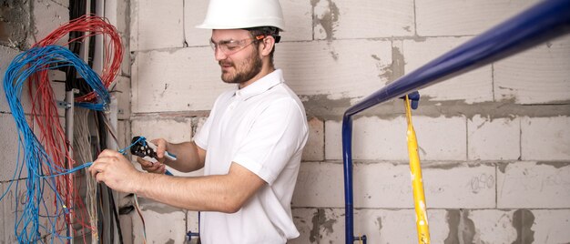 Elektriker arbeitet in der Nähe der Platine mit Drähten. Installation und Anschluss von Elektrik.