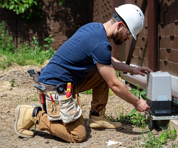 Elektriker Builder bei der Arbeit, Wartung der Rumpf Industrie Schalttafel. Professionell in Overalls mit einem Elektrikerwerkzeug.