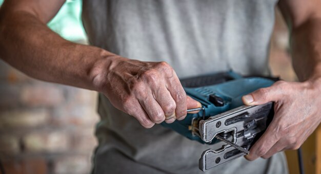 Elektrische Stichsäge mit einer Säge für Holz in den Händen eines Zimmermanns.