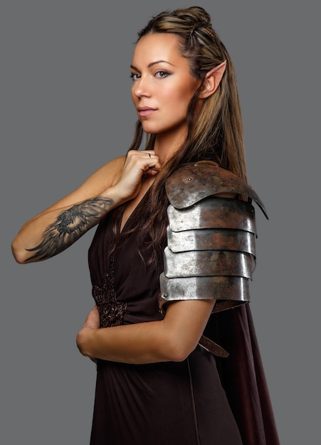Elfenfrau in Rüstung mit Tätowierung auf ihrer Hand. Isoliert auf grauem Hintergrund.
