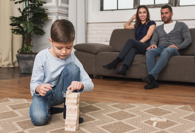 Eltern, die den Sohn spielt jenga aufpassen