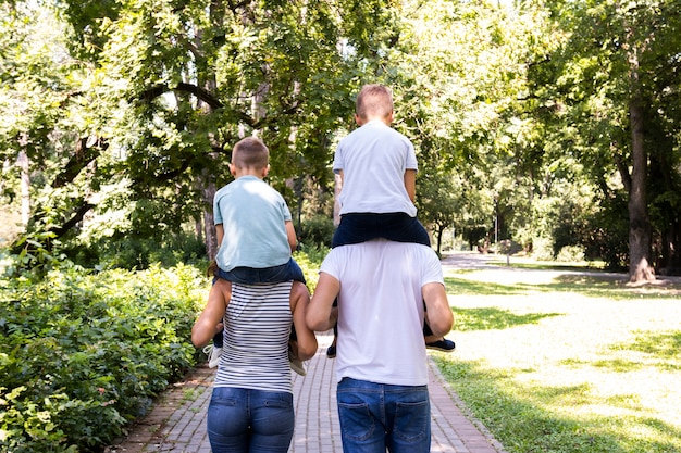 Eltern, die ihre Kinder auf Schultern tragen