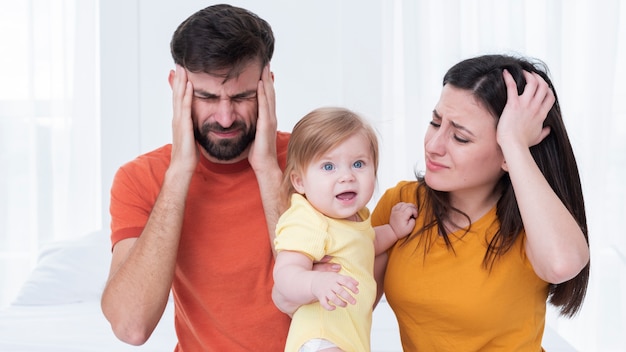 Eltern mit dem Baby, das Kopfschmerzen hat