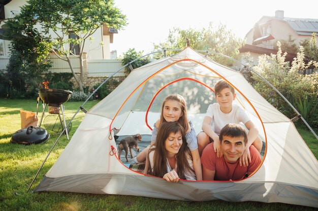 Eltern mit ihren Kindern, die auf Zelt während des Picknicks liegen
