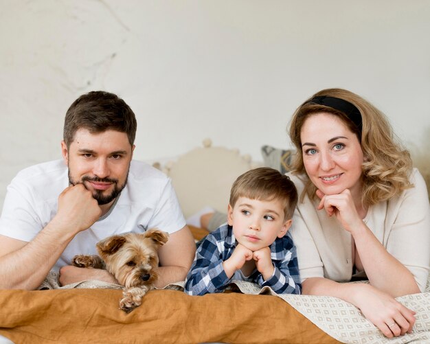 Eltern mit Kind und Hund sitzen im Bett