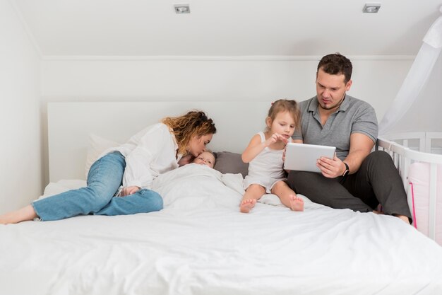 Eltern sitzen mit Kindern im Bett