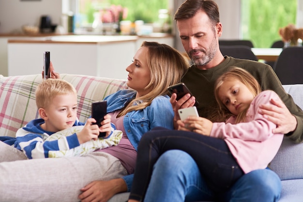 Eltern und Kinder mit Handy im Wohnzimmer