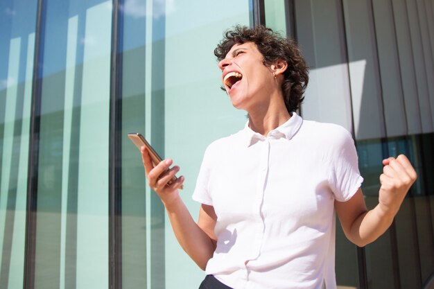 Emotionale Geschäftsfrau mit Smartphone