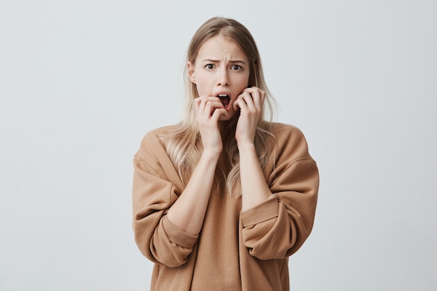 Emotionale hübsche Frau mit blonden Haaren, betäubt. Negative Emotionen