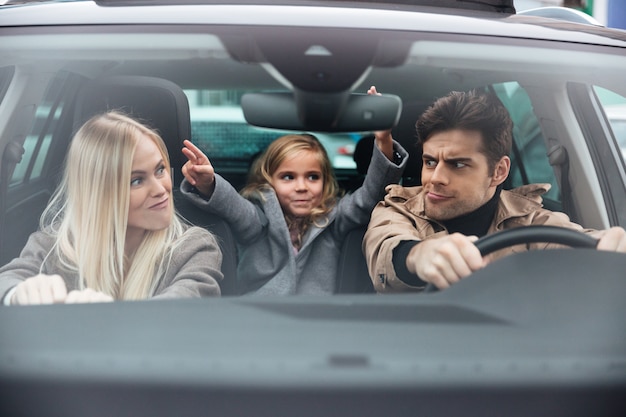 Emotionaler junger Mann, der im Auto mit seiner lustigen Frau sitzt