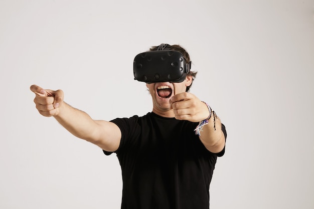 Emotionaler junger Spieler im VR-Headset und im schwarzen unbeschrifteten T-Shirt schreit beim Spielen
