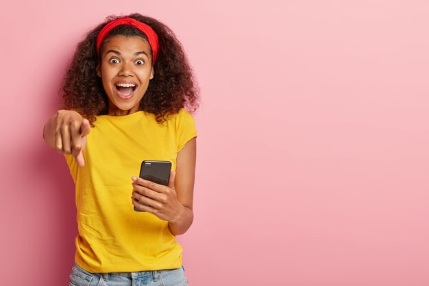 Emotionales junges Mädchen mit dem lockigen Haar, das im gelben T-Shirt aufwirft