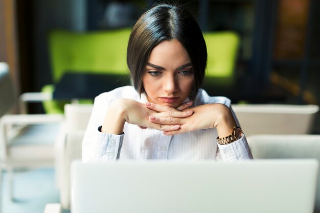 Emotionslose Frau, die Laptop im Café verwendet